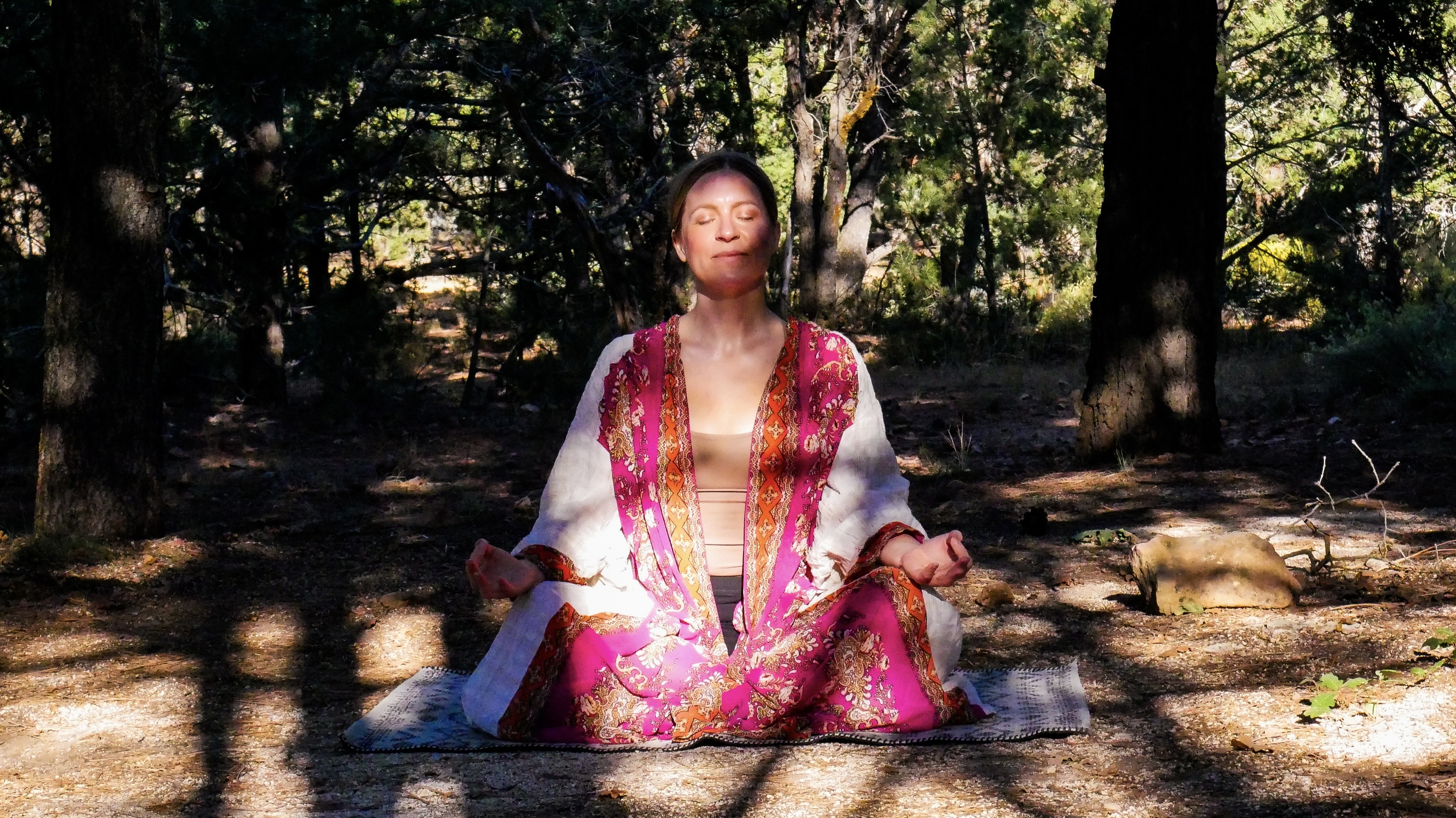 Heather in seated meditation beneath juniper trees